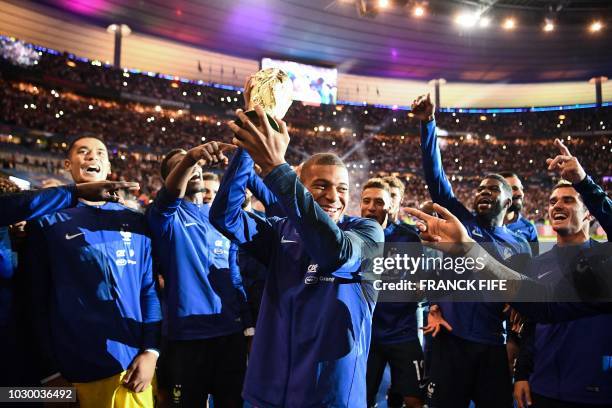 France's midfielder Kylian Mbappe and team players celebrate as they do a lap of honour during a ceremony to celebrate the victory of the 2018 World...