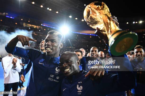 France's midfielder Paul Pogba and France's defender N'golo Kante hold the 2018 World Cup trophy as they celebrate during a ceremony for the victory...