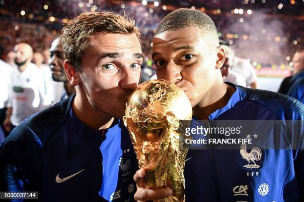 France's forward Antoine Griezmann and France's midfielder Kylian Mbappe kiss the 2018 World Cup trophy as they celebrate during a ceremony for the...