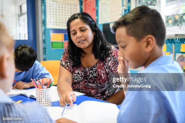aboriginal basisschool leraar helpen jonge jongen in de klas - school teacher stockfoto's en -beelden