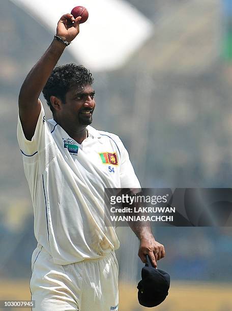 Sri Lankan cricketer Muttiah Muralitharan waves at the end of the Indian team's first innings during the fourth day of the first Test match between...