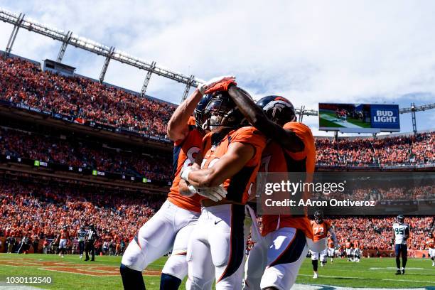 Phillip Lindsay of the Denver Broncos celebrates his first career touchdown with teammates Jeff Heuerman and DaeSean Hamilton against the Seattle...