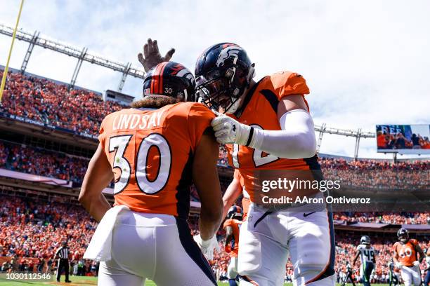 Phillip Lindsay of the Denver Broncos celebrates his first career touchdown with teammate Garett Bolles against the Seattle Seahawks during the first...