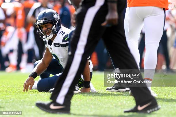 Russell Wilson of the Seattle Seahawks sits on the turf after taking heat from Todd Davis of the Denver Broncos during the Broncos 27-24 win at...