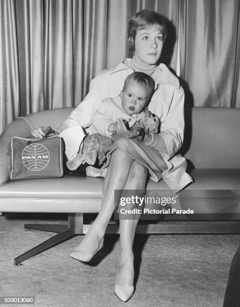 Actress Julie Andrews clutching a Pan Am flight bag and holding her seventeen-month-old daughter Emma Kate Walton at Kennedy International Airport in...