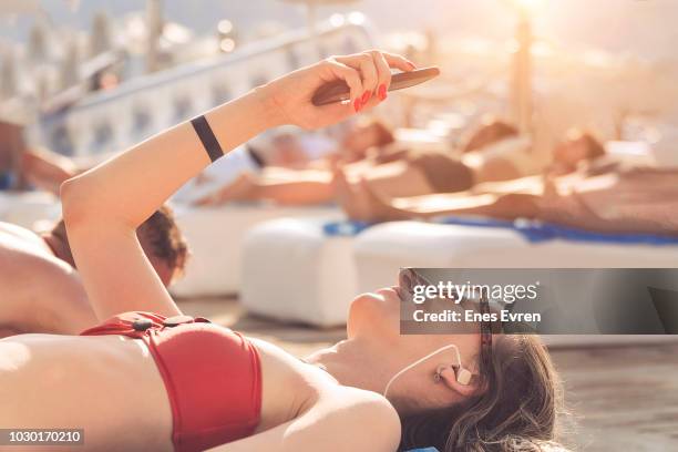 vrouw nemen selfie op het strand tijdens het zonnen. droomvakantie in tropisch land - urban beach stockfoto's en -beelden