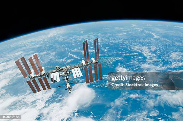 february 19, 2010 - the international space station backdropped by earth's horizon and the blackness of space. - estación espacial internacional fotografías e imágenes de stock