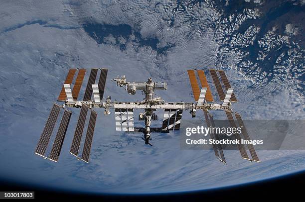 international space station set against the background of a cloud covered earth. - estación espacial internacional fotografías e imágenes de stock