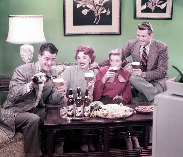 Two couples smile and drink beer in this advertisement piece for Goebel beer, 1948. One man pours himself a glass of beer, while his friends watch...