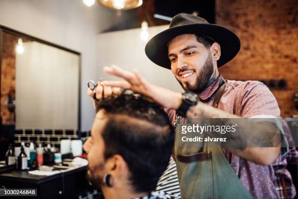 smiling barber cutting customer's hair in salon - hair salon stock pictures, royalty-free photos & images