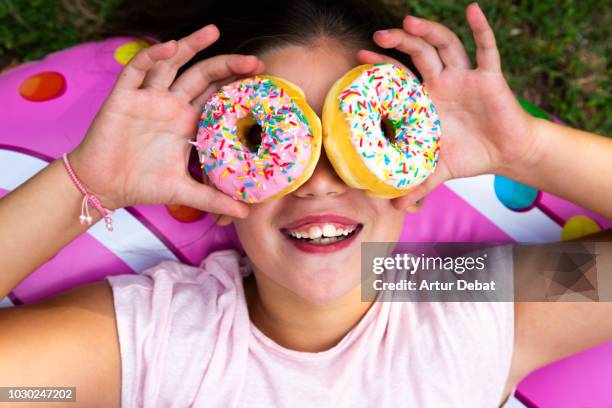 funny girl using colorful donuts like eyeglasses. - boulangerie industrielle photos et images de collection