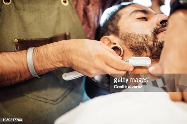 barber shaving man with straight razor in salon - straight razor stock pictures, royalty-free photos & images