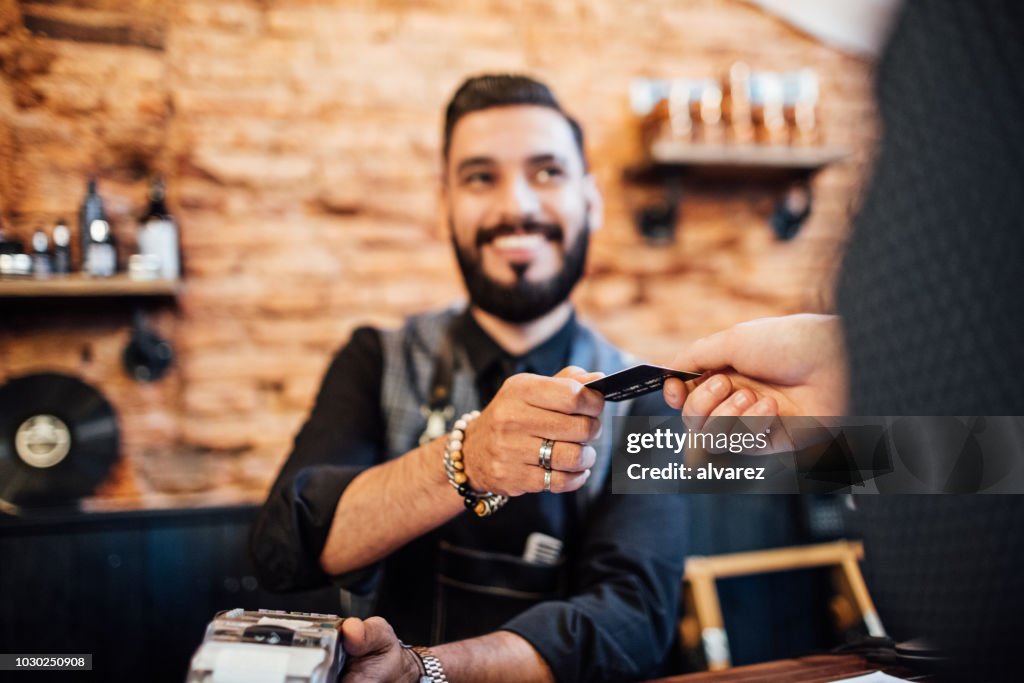 Hairdresser receiving credit card from customer