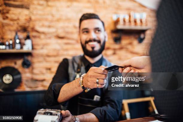 hairdresser receiving credit card from customer - debit cards credit cards accepted stock pictures, royalty-free photos & images