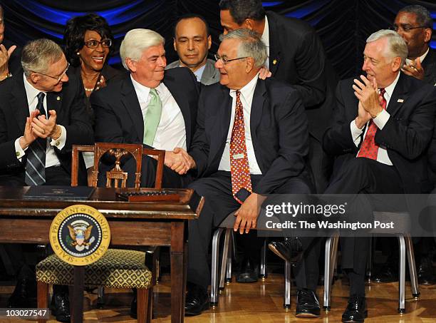 Washington, DC Senators Chris Dodd, 2nd left, and Barney Frank, 2nd left, shake hands while receiving an ovation as President Obama signs the...