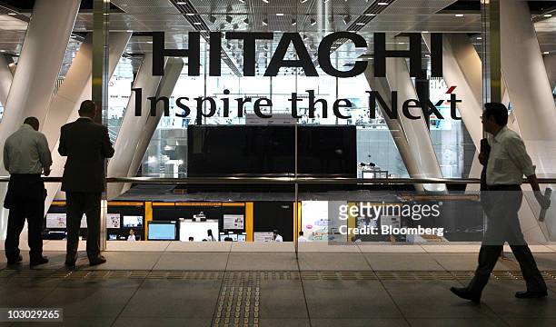 Visitors walk past the logo for Hitachi Ltd. Displayed at the Hitachi uVALUE Convention 2010 in Tokyo, Japan, on Thursday, July 22, 2010. Hitachi is...