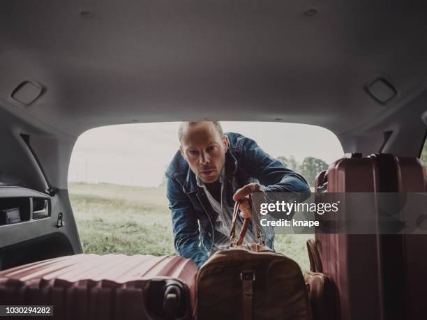 mann in seinem gepäck koffer in seinem auto bereit für die reise packen - luggage trunk stock-fotos und bilder