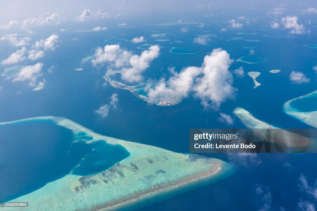 Maldives island aerial view. Atolls and blue lagoon in tropical sea. Drone or airplane view