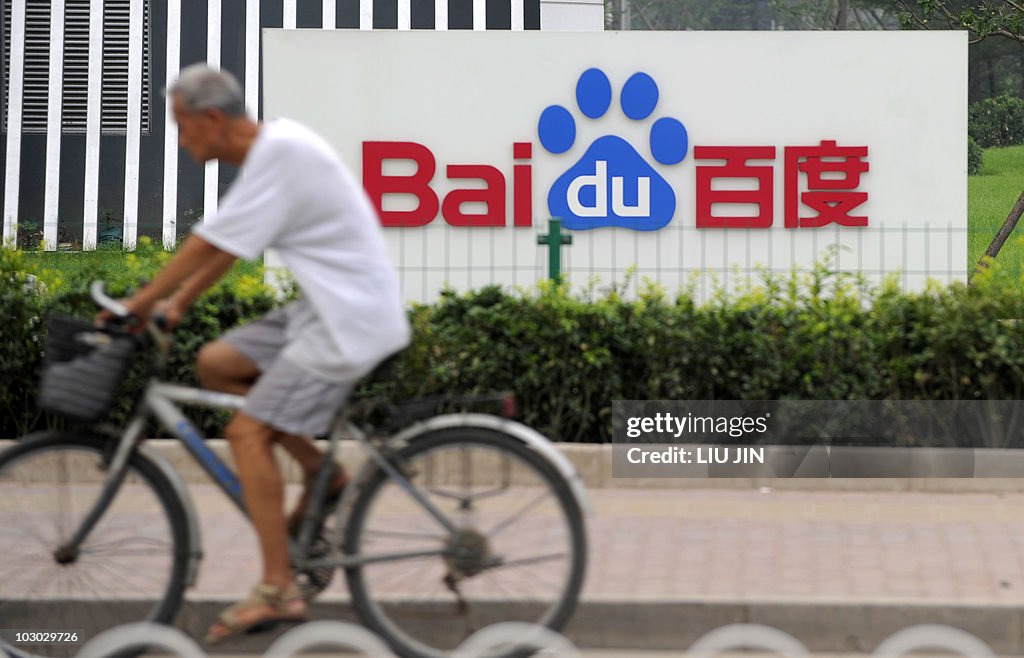 A man rides a bicycle past the logo of B
