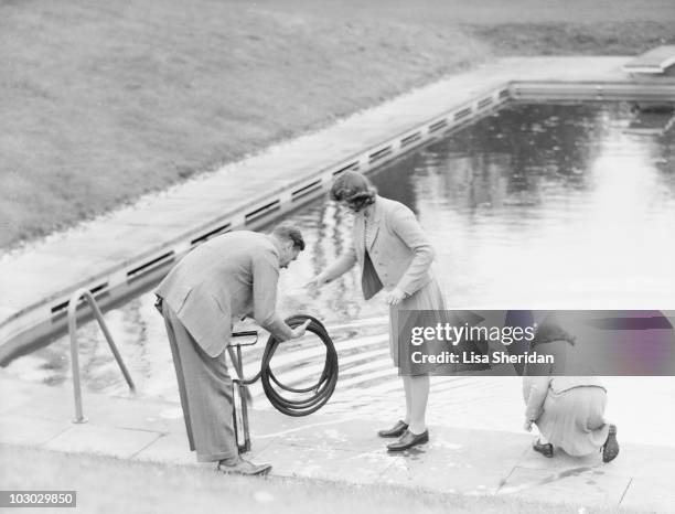 King George VI, Princess Elizabeth and Princess Margaret collect water from a swimming pool at the Royal Lodge in Windsor Castle, England on April...