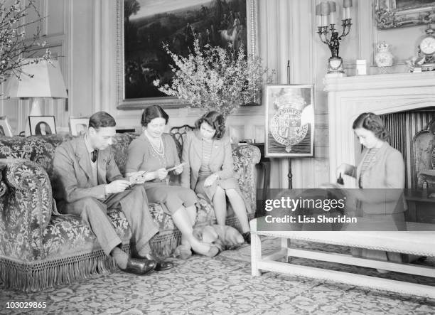 King George VI, Queen Elizabeth and Princess Elizabeth sitting on a couch as Princess Margaret grooms a pet dog at the Royal Lodge in Windsor Castle,...