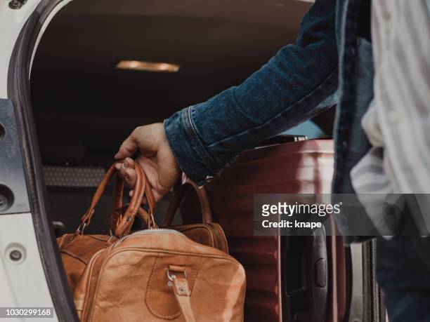 man verpakken in zijn koffer bagage in zijn auto klaar voor road trip - pak stockfoto's en -beelden