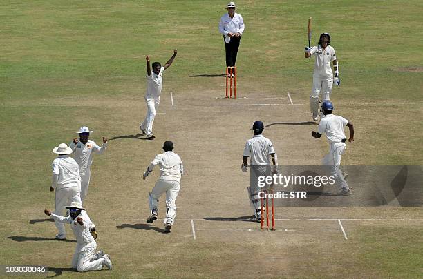 Sri Lankan cricketer Muttiah Muralitharan celebrates with teammates on claiming his 800th Test wicket with the dismissal of Indian cricketer Pragyan...