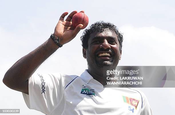 Sri Lankan cricketer Muttiah Muralitharan holds up the cricket ball as he walks back to the pavilion at the end of India's second innings during the...