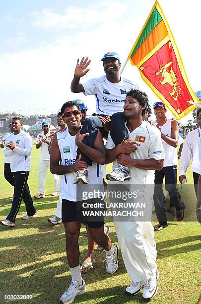 Sri Lankan cricketer Muttiah Muralitharan waves to the crowd as his teammates captain Kumar Sangakkara and Damika Prasad carry him around the pitch...