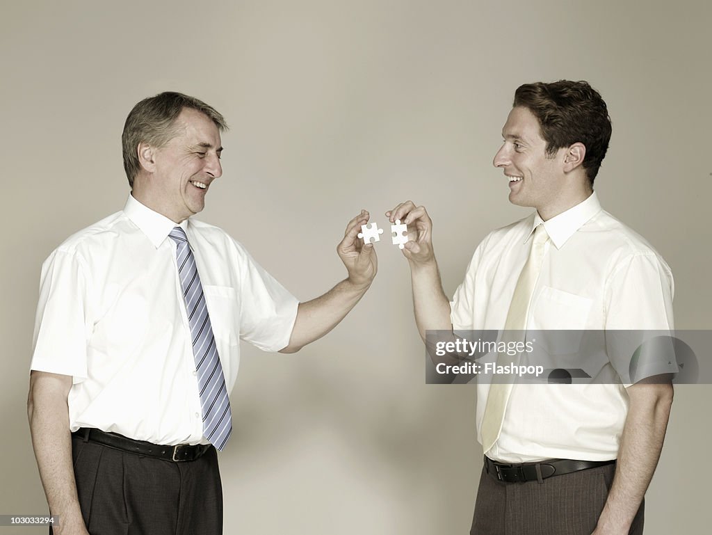 Two businessmen piecing together a jigsaw