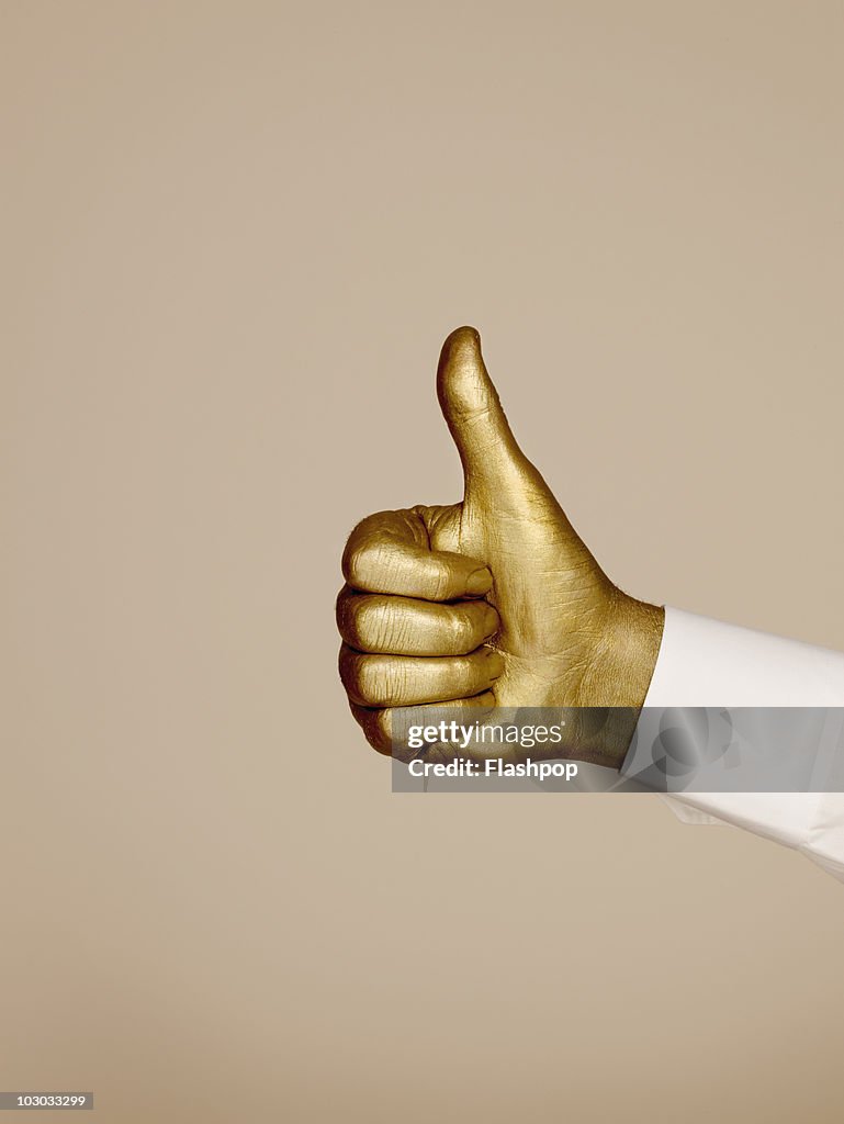 Golden hand making "thumbs up" gesture