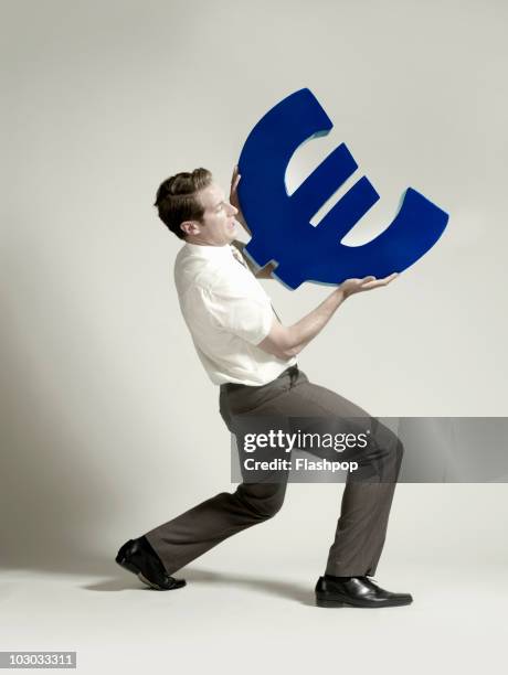 businessman lifting large euro symbol - weight lifting imagens e fotografias de stock