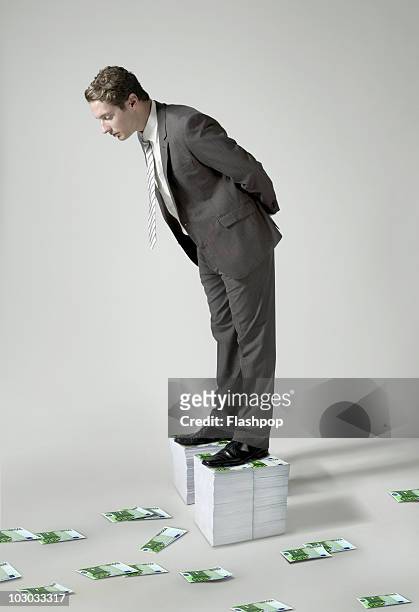 businessman standing on large pile of euro notes - bending stock pictures, royalty-free photos & images