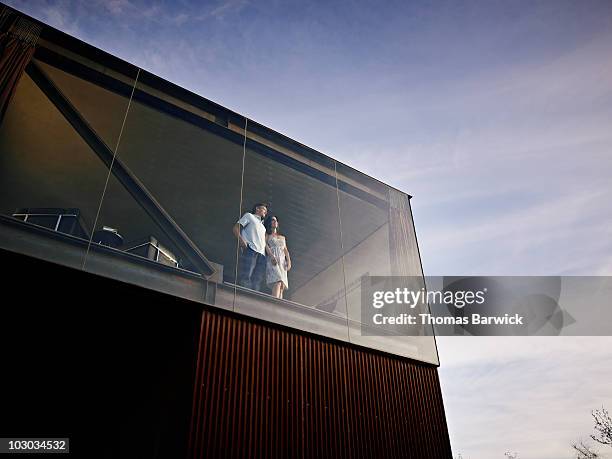 husband and wife standing looking out window  - looking outside window stock-fotos und bilder