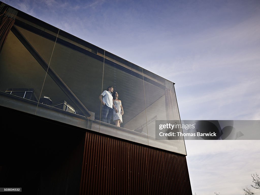 Husband and wife standing looking out window 