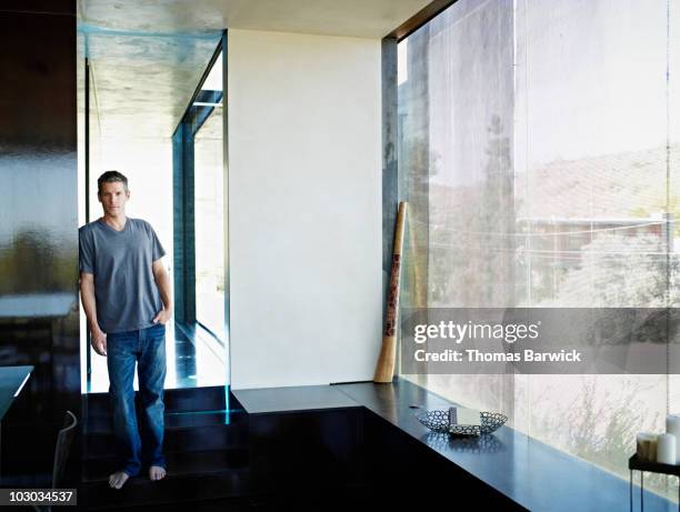 man standing barefoot in hallway of home - true luxury stock-fotos und bilder