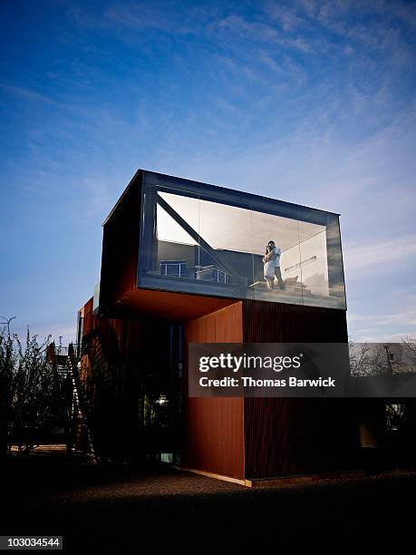 couple embracing in window of bedroom of home - einfamilienhaus stock-fotos und bilder