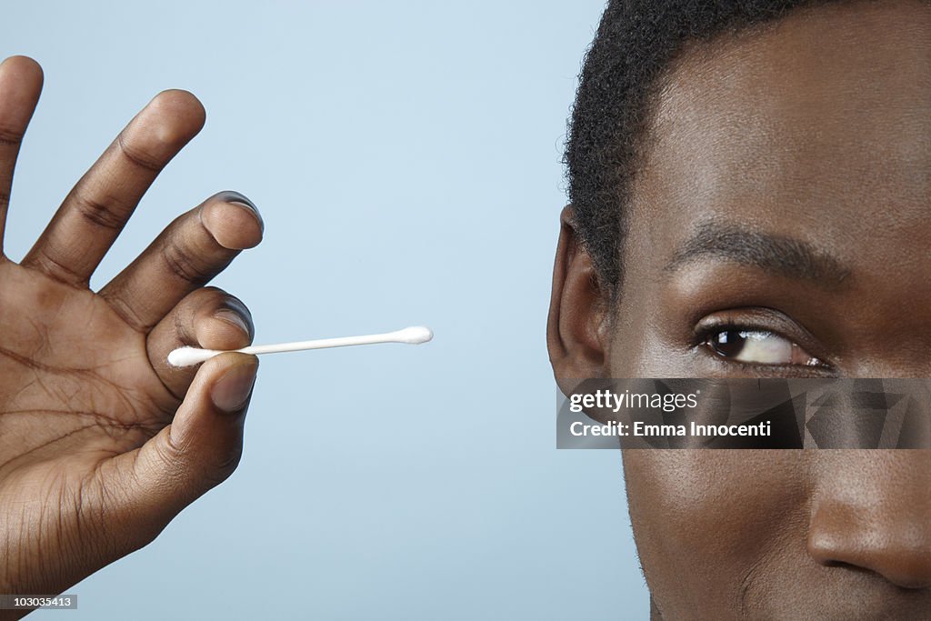 Close up young man holding cotton bud