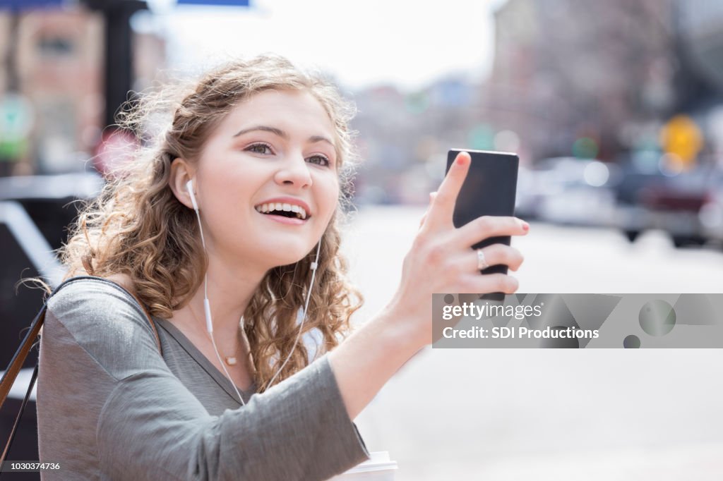 Junge Frau verwendet mobile app, um eine Fahrt zu Hagel