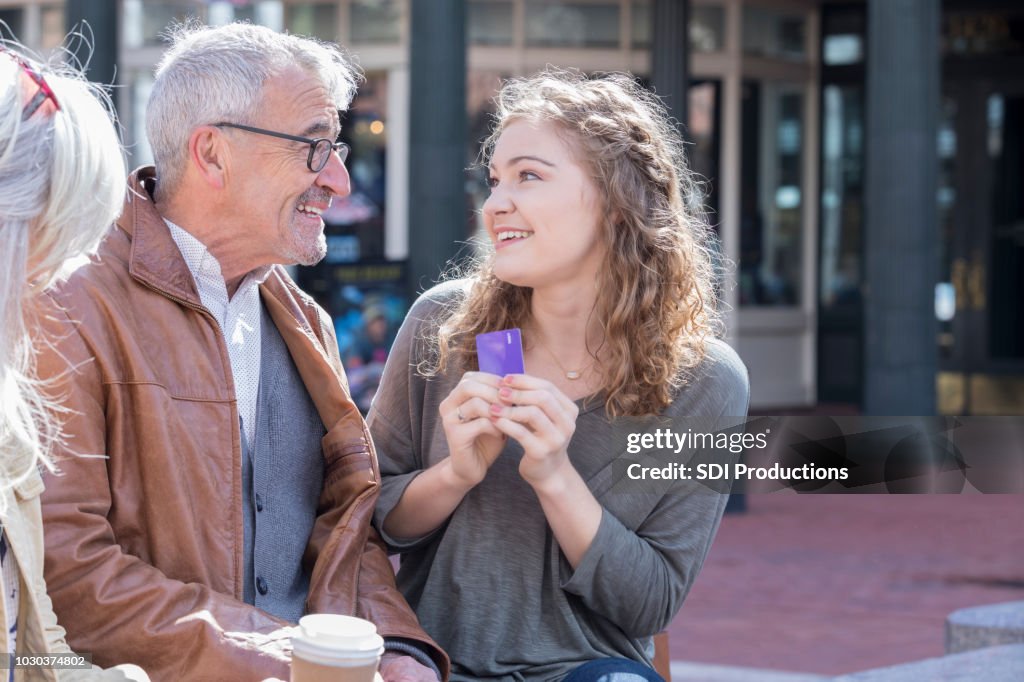Excited young woman receives credit card from grandfather