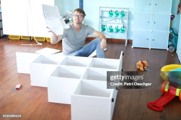 a man getting frustrated with the instruction manual. - building shelves stock-fotos und bilder