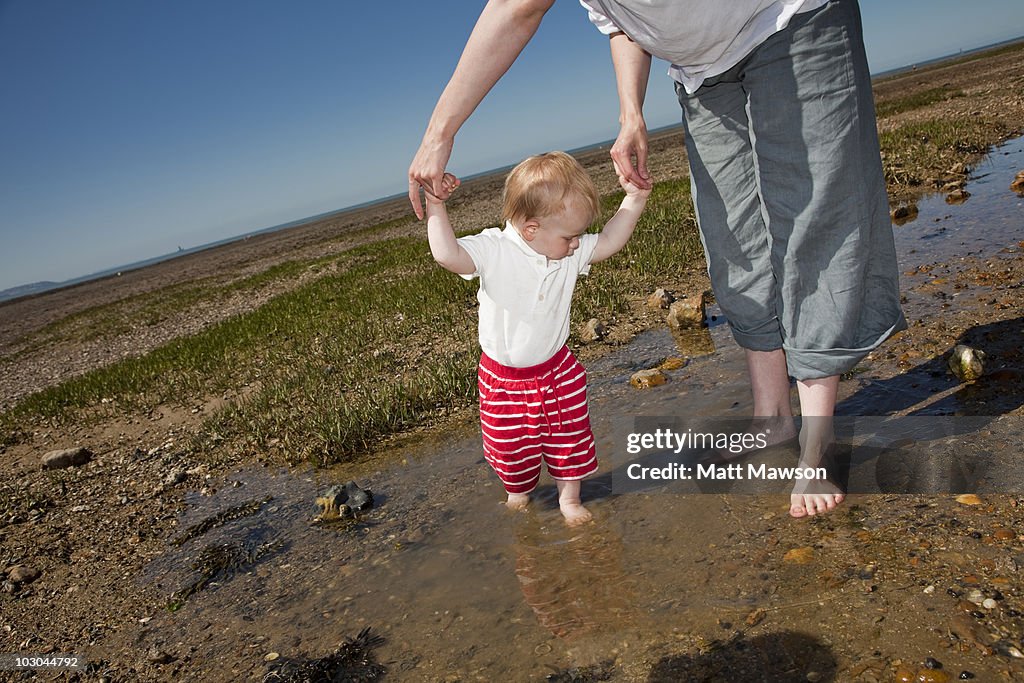 Mother and son play in tidal pool on beach