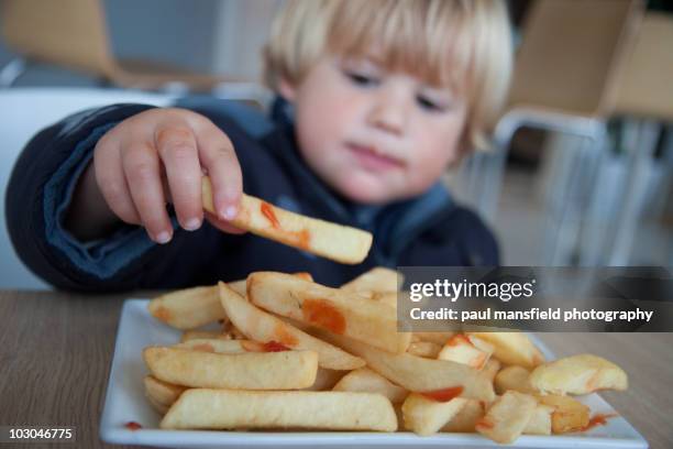 young boy eating chips - frites stock pictures, royalty-free photos & images