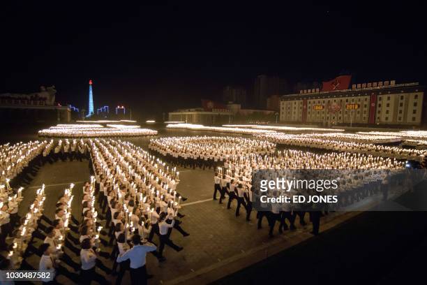 Participants perform in a torch parade on Kim Il Sung square in Pyongyang on September 10, 2018. - Thousands of North Koreans wielding burning...