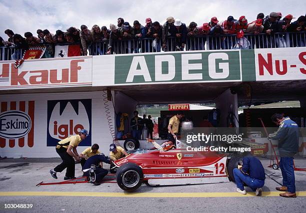 Gilles Villeneuve gestures for adjustments to be made on the Scuderia Ferrari SpA SEFAC Ferrari 312T4 as spectators look on during practice for the...