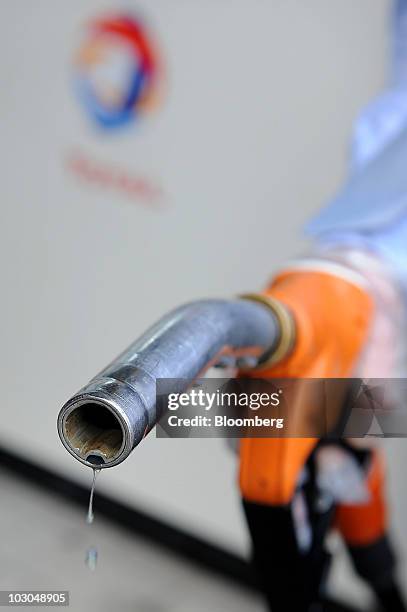 Customer holds a fuel nozzle at a Total SA gas station in Paris, France, on Thursday, July 22, 2010. The company, Europe's biggest oil refiner,...