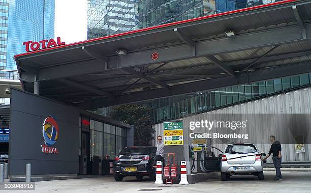 Customers fill their cars with fuel at a Total SA gas station in Paris, France, on Thursday, July 22, 2010. The company, Europe's biggest oil...