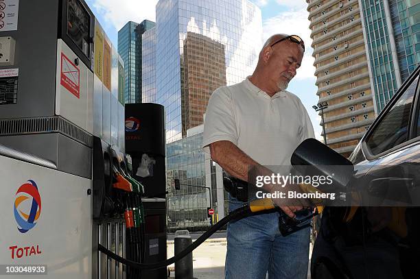 William Shapman fills his car with fuel at a Total SA gas station in Paris, France, on Thursday, July 22, 2010. The company, Europe's biggest oil...