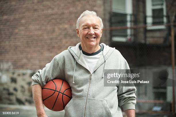 elderly man holding basket ball - basketball portrait stockfoto's en -beelden