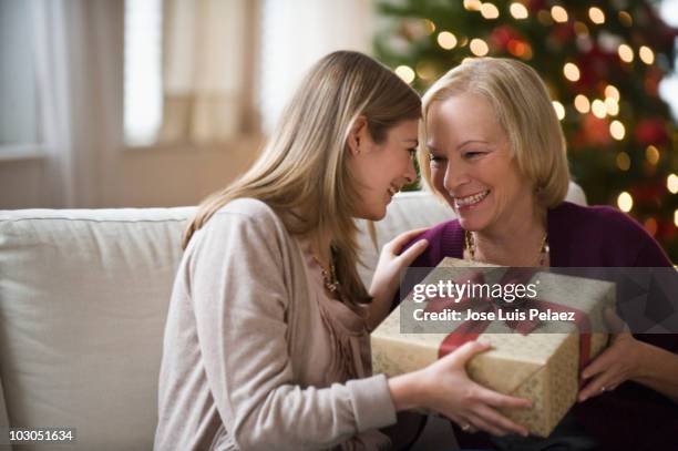 mother and daughter sitting on the couch  exchangi - gift giving stock pictures, royalty-free photos & images